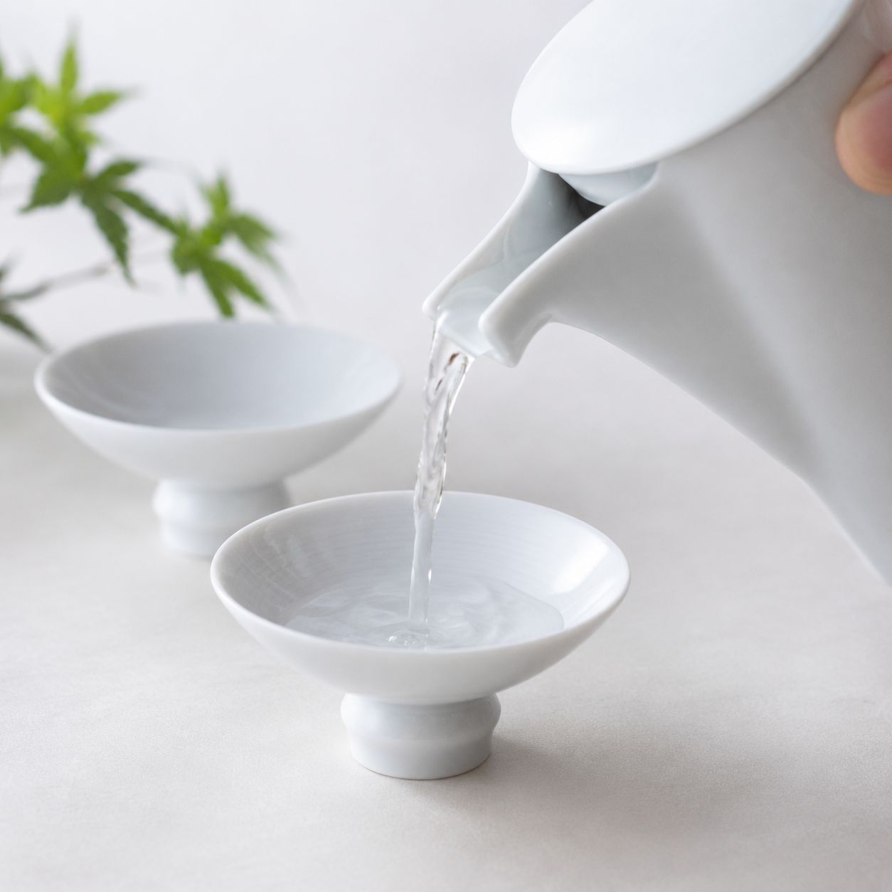 白磁の酒器に日本酒を注いでいる使用シーン